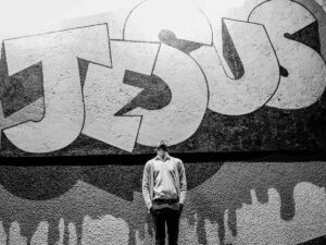 Ein Mann blickt auf ein Graffiti, das den Namen "Jesus" darstellt