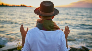 Mann mit Hut am Meer von hinten