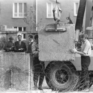 Schwarzwei?-Foto, das einen Soldaten, Männer in Anzügen und zwei Männer, die einen Stein tragen zeigt.