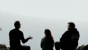 Eine Silhouette von Menschen, die sich sitzend vor einem hellen Hintergrund unterhalten